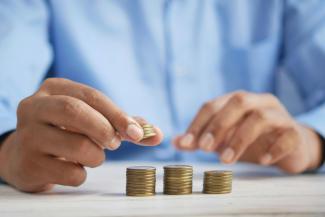 a person stacking coins on top of a table by Towfiqu barbhuiya courtesy of Unsplash.